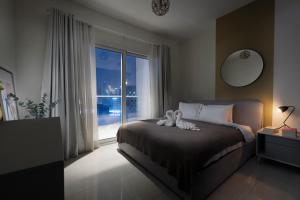 een slaapkamer met een bed en een groot raam bij Unlock Metropolis Business Bay in Dubai