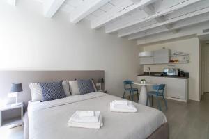 a bedroom with a large white bed and a kitchen at Residenza SubitoSanto - Appartamento 2A "Angelina" in Padova
