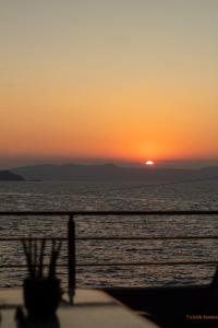 een zonsondergang boven de oceaan met de zon in de verte bij Tabak home Sea side apartment in Chania