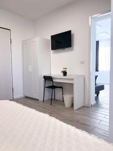Dieses weiße Zimmer verfügt über einen Schreibtisch und einen TV an der Wand. in der Unterkunft A casa di Asja in Terni