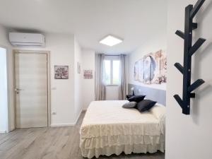 biała sypialnia z łóżkiem z czarnymi poduszkami w obiekcie A casa di Asja w mieście Terni