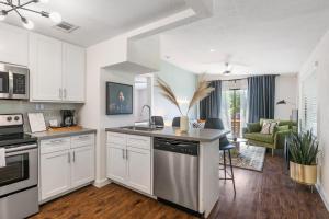 a kitchen with white cabinets and a living room at Abode Houston - Norfolk in Houston