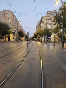 an empty street with streetcar tracks in a city at Jerusalem M in Jerusalem