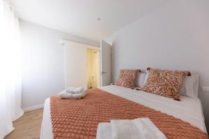 ein Schlafzimmer mit einem großen Bett mit orangefarbenen und weißen Kissen in der Unterkunft Bravissimo Eiximenis, with beautiful terrace and views in Girona