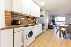 a kitchen with white cabinets and a washer and dryer at Bravissimo Eiximenis, with beautiful terrace and views in Girona