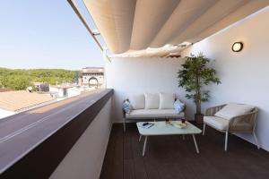 ein Wohnzimmer mit einem Sofa und einem Tisch auf dem Balkon in der Unterkunft Bravissimo Eiximenis, with beautiful terrace and views in Girona