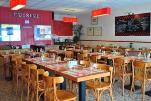 een eetkamer met houten tafels en stoelen bij Hotel Les Voyageurs in Les Sables-dʼOlonne