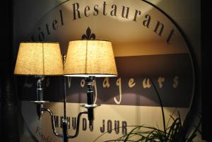 莱萨布勒-多洛讷Hotel Les Voyageurs的镜子前两盏灯,上面有标志