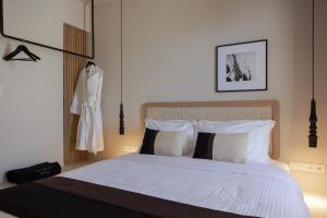 una camera da letto con letto, lenzuola e cuscini bianchi di Nimbus Lumen a Super Paradise Beach
