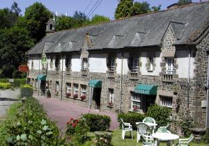 un ancien bâtiment avec des tables et des chaises devant lui dans l'établissement Le Vieux Moulin, à Hédé