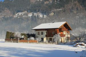 ein Haus mit schneebedecktem Dach im Schnee in der Unterkunft Haus Schönegger in Dorfgastein