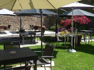 a group of tables and chairs with umbrellas at Le Vieux Moulin in Hédé