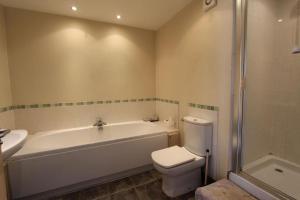a bathroom with a tub and a toilet and a sink at 1 Coach House Mews - Matlock Bath in Matlock Bank
