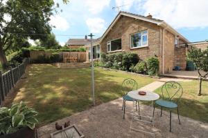 een achtertuin met een tafel en stoelen voor een huis bij Hilltops in Wroxall