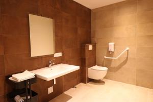 La salle de bains est pourvue d'un lavabo, de toilettes et d'un miroir. dans l'établissement Le Vieux Moulin, à Hédé