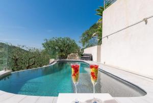 two drinking glasses with flowers in them next to a swimming pool at Villa des Oliviers in Nice