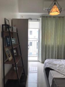 a bedroom with a bed and a book shelf next to a window at Cozy 2 BR high floor end unit with balcony at SM Southmall in Manila