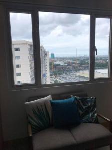 a couch sitting in a room with three windows at Cozy 2 BR high floor end unit with balcony at SM Southmall in Manila