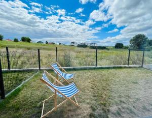 two chairs sitting next to a fence in a field at Apartament Sunnyside Rewa in Rewa