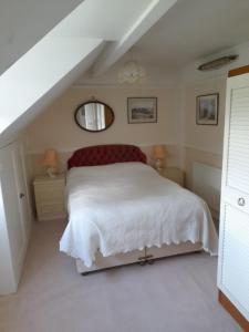 a bedroom with a white bed and a staircase at Fern Cottage in Scalby