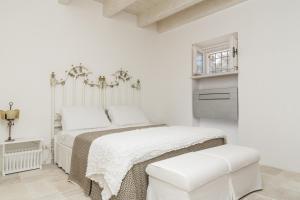 a white bedroom with a bed and a white chair at Trulleria Tagliente in Alberobello