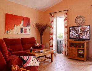 a living room with a red couch and a tv at Villas Las Golondrinas in Cala'n Bosch