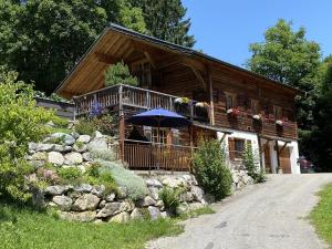 una casa de madera con una sombrilla delante de ella en Chalet Tschengla, en Bürserberg