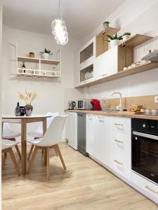 een keuken met witte kasten en een tafel en stoelen bij KeSa Apartment in Korçë