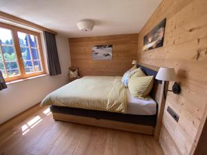1 dormitorio con 1 cama con pared de madera en Chalet Tschengla, en Bürserberg