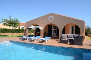 a villa with a swimming pool with chairs and an umbrella at Villas Las Golondrinas in Cala'n Bosch
