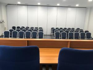 une salle d'audience vide avec des chaises bleues devant dans l'établissement Royal Hotel, à Cosenza