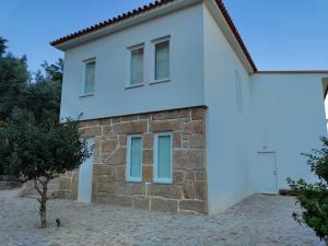 uma casa branca com janelas azuis e uma árvore em Vila Real House em Vila Real