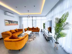 sala de estar con 2 sofás y TV en Olivia Chalet فلة أوليفيا en Al ‘Aqar