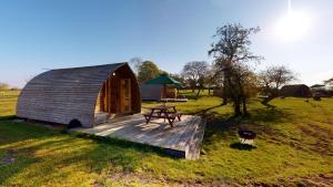 a small wooden cabin with a picnic table on a field at Hill Farm and Orchard in Leighton Buzzard