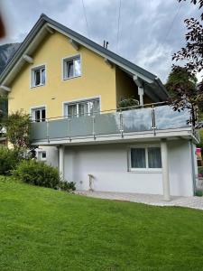 een geel en wit huis met een balkon bij Ferienwohnung Laura in Wald am Arlberg