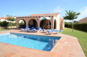 a villa with a swimming pool with chairs and an umbrella at Villas Las Golondrinas in Cala'n Bosch