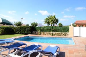 a swimming pool with lounge chairs and a swimming pool at Villas Las Golondrinas in Cala'n Bosch