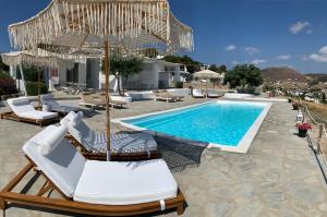 a pool with chaise lounge chairs and an umbrella at Blue Bay Heliolithos in Parikia