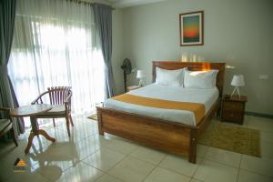 a bedroom with a bed and a table and a chair at CWEZI BY THE LAKE in Entebbe