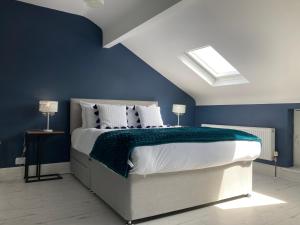 a bedroom with a large bed with blue walls at Tynwald Beachside Town House, West Kirby by Rework Accommodation in West Kirby