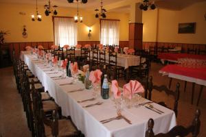 uma mesa longa numa sala com mesas e cadeiras brancas em Hotel Cantaleone em San Michele allʼAdige