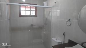 baño blanco con ducha y ventana en Pousada Blues, en Ipiabas