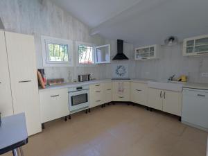 une cuisine avec des armoires blanches et des appareils électroménagers blancs dans l'établissement Villa 'Andercool' avec piscine utilisable en toutes saisons, à Andernos-les-Bains