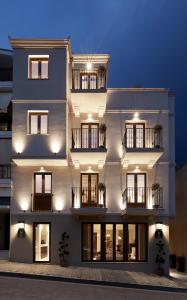 a white building with windows and balconies at night at The Storyteller Boutique House in Kalabaka