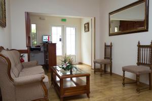 ein Wohnzimmer mit 2 Stühlen, einem Tisch und einem Spiegel in der Unterkunft Hostal Dulcinea in Esquivias