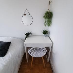 a white bedside table with a mirror and plants at Chambre Voyage tout confort pres de saint Marceau in Saint-Jean-le-Blanc