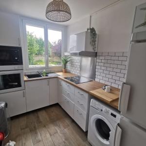 a kitchen with white cabinets and a washer and dryer at Chambre Voyage tout confort pres de saint Marceau in Saint-Jean-le-Blanc