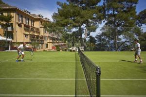 two men playing tennis on a tennis court at Splendido, A Belmond Hotel, Portofino in Portofino