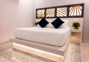 a bedroom with a white bed with blue pillows at The Garden by DOT Suites in Santa Marta
