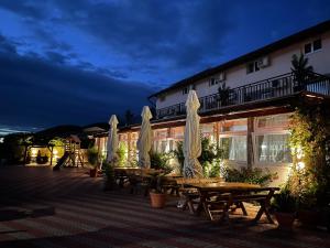a hotel patio with tables and umbrellas at night at Pensiunea Danubio in Moldova Nouă